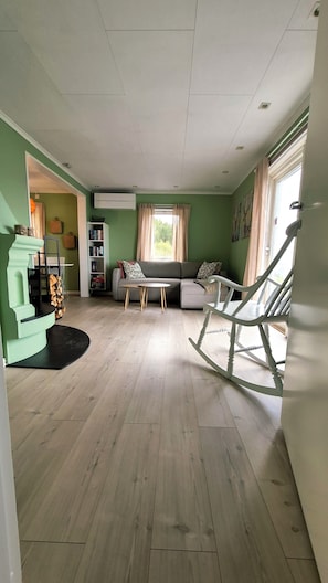 A living room with a sectional sofa, a rocking chair, a small table, and a bookshelf.