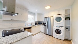 Una cocina moderna con armarios blancos, electrodomésticos de acero inoxidable, lavavajillas integrado y encimera de granito.