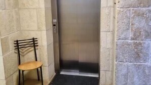 Un ascensor estrecho con una silla en un pasillo de paredes de piedra.