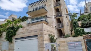 A multi-story residential building with a garage, balconies, and a gated entrance. - Cute Studio near Yad Vashem. Free street parking. (Jerusalem)