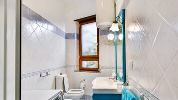 Un baño pequeño con lavadora, inodoro y lavamanos.