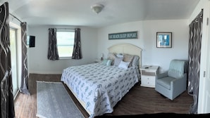 A bedroom with a bed, a nightstand, a chair, a rug, and a sign on the wall. - 1 Mile to Anna Maria Island, 2 bd rm 2 bath 3 Queen beds, sleeps 6 comfortably. (Bradenton)