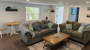 A living room with two couches, a wooden coffee table, and a dining table with chairs. - 1 Mile to Anna Maria Island, 2 bd rm 2 bath 3 Queen beds, sleeps 6 comfortably. (Bradenton)