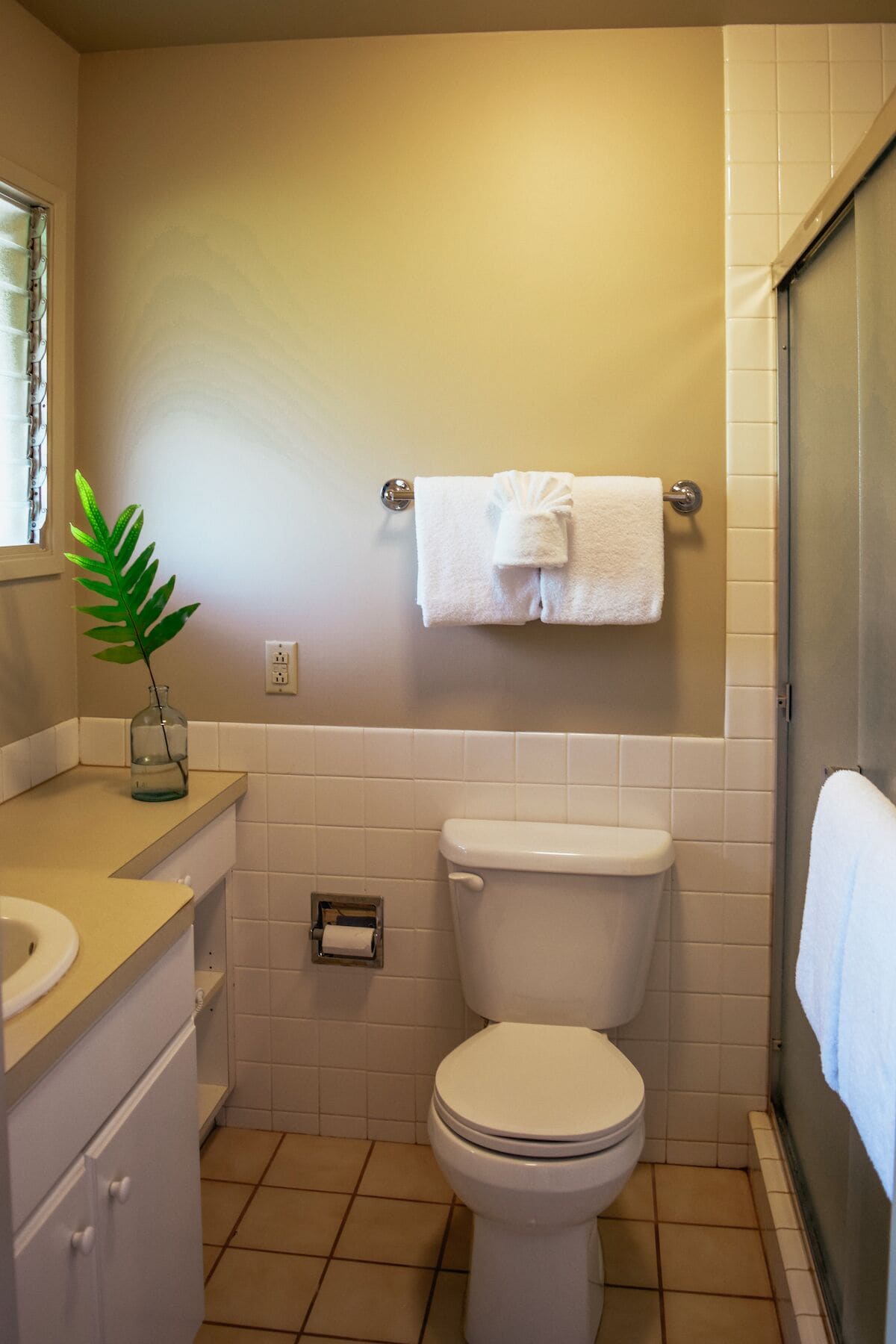 A small, clean bathroom with a toilet, sink, and a towel rack.
