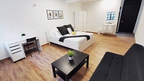 A modern, well-lit room with a bed, a black sofa, a small desk, and a potted plant. - Room-cozy Room With Terrace 5 (Mexico City)