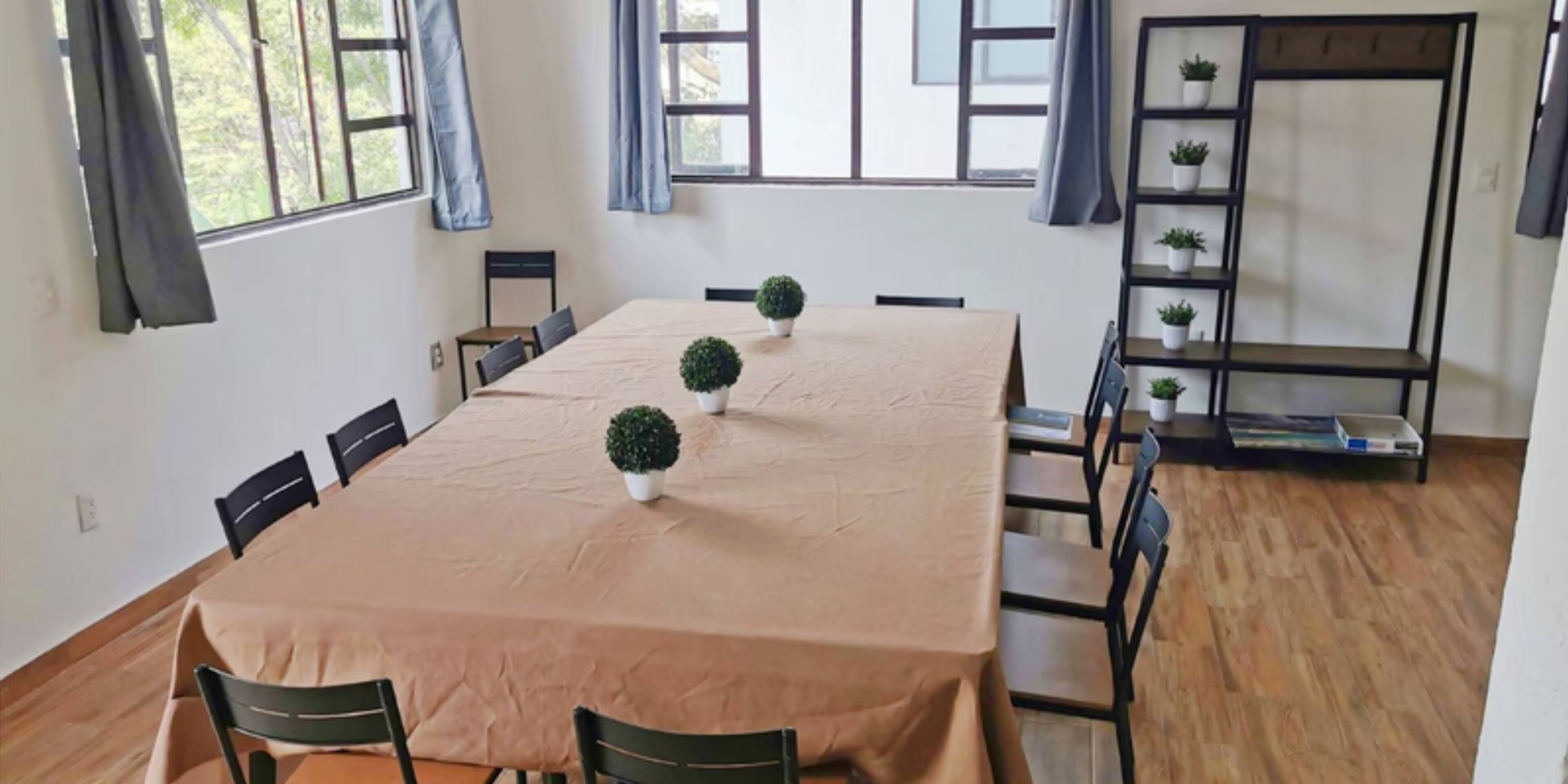 Un espace repas comprenant une longue table, des chaises, des plantes en pot et une bibliothèque.