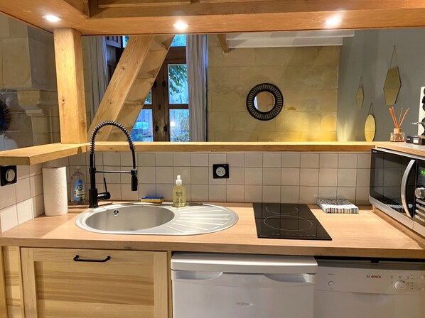 A modern kitchen with a wooden countertop, a sink, a Bosch dishwasher, and a microwave.