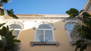 Eine Gebäudefassade mit drei Rundbogenfenstern und einem zentralen Balkon.