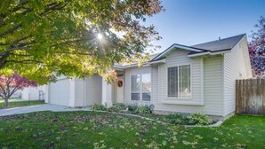 Une maison de plain-pied avec un jardin devant, une clôture en bois et un arbre.