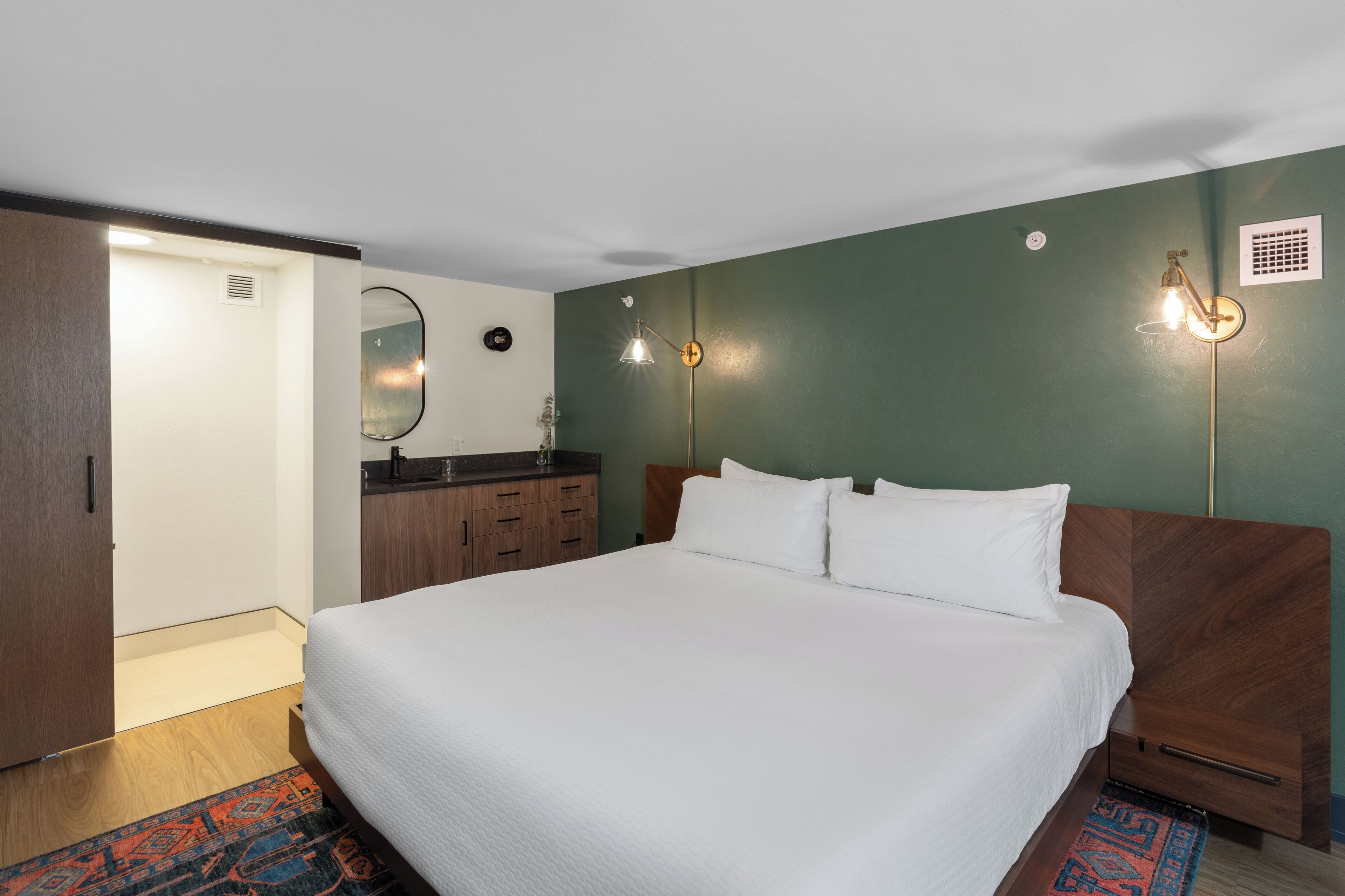 A bedroom with a large bed, wooden headboard, a dresser, and a mirror on the wall.
