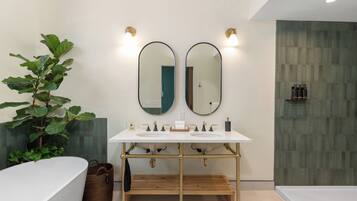 A modern bathroom with a white vanity, two mirrors, a bathtub, and a shower area.