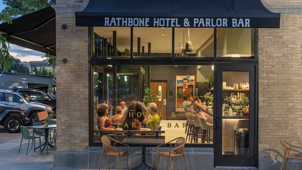The exterior of the Rathbone Hotel & Parlor Bar with a brick facade, large windows, and outdoor seating area. - The Rathbone Hotel (Montrose)