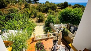 Une terrasse avec vue sur la mer, entourée de verdure et dotée d’une balustrade blanche.