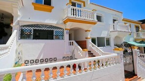 Un bâtiment blanc doté de balcons et d’une entrée fermée par un portail.