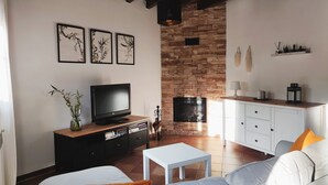A living room with a television, a fireplace, a sofa, and a coffee table.