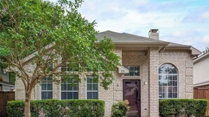 A two-story house with a brick facade, numbered 551, featuring a front door, two windows, and a small porch area. - Updated, Comfortable, and Quiet Space close to DFW International Airport! (Coppell)