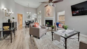 A spacious living room with a fireplace, a dining area, and a TV mounted on the wall. - Updated, Comfortable, and Quiet Space close to DFW International Airport! (Coppell)