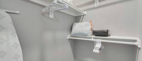 A closet with white shelves, a hanging rack, and a wooden floor.