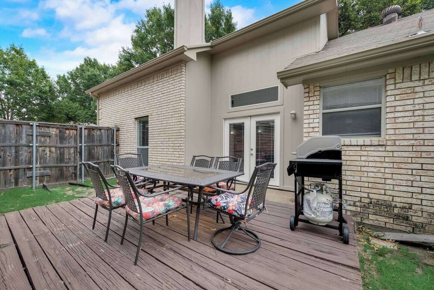 Une terrasse avec une table et des chaises, un barbecue et une plateforme en bois.