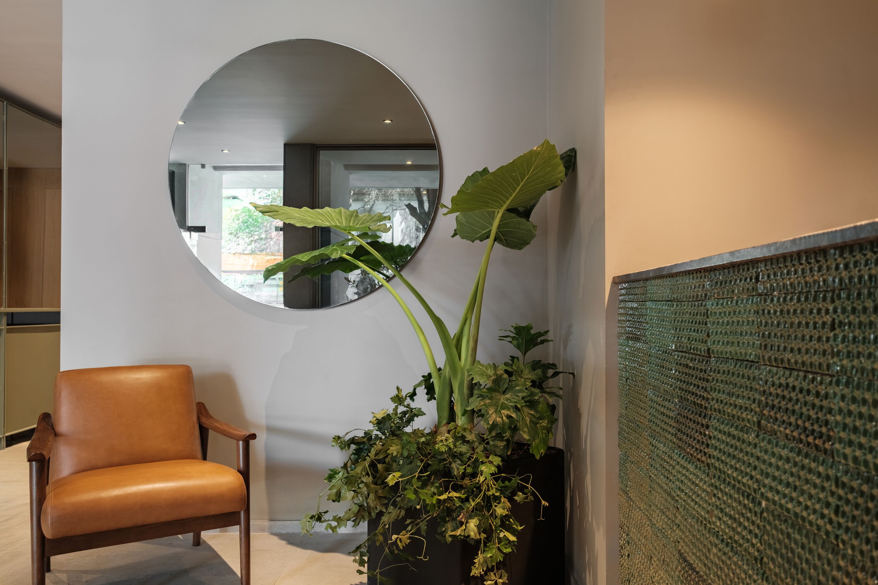 Un intérieur moderne avec un fauteuil en cuir, un grand miroir et une plante en pot.