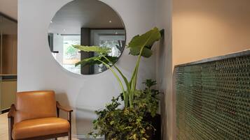 Un interior moderno con un sillón de cuero, un espejo grande y una planta en maceta.