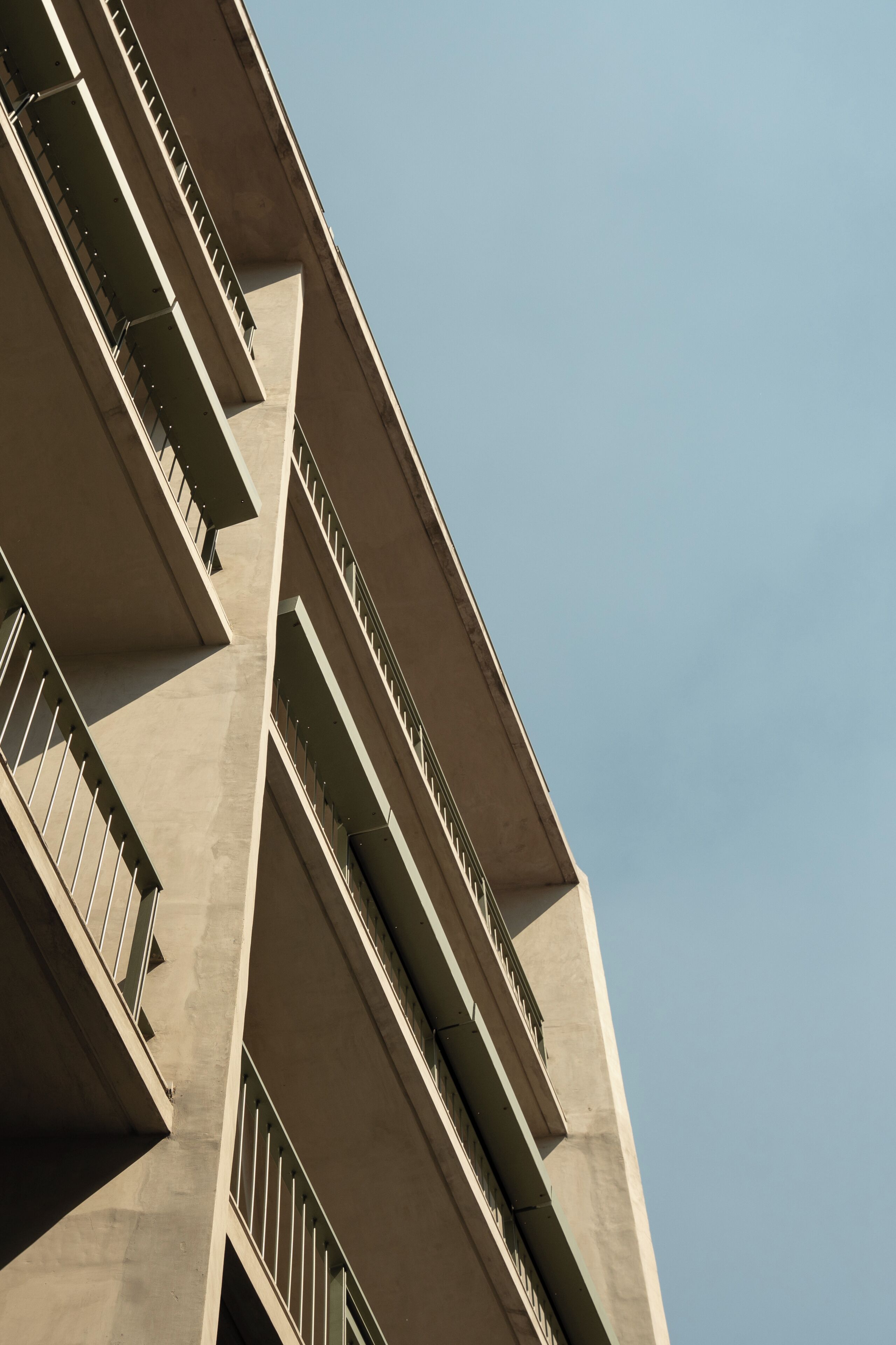 A high-rise building with multiple balconies and a clear sky.
