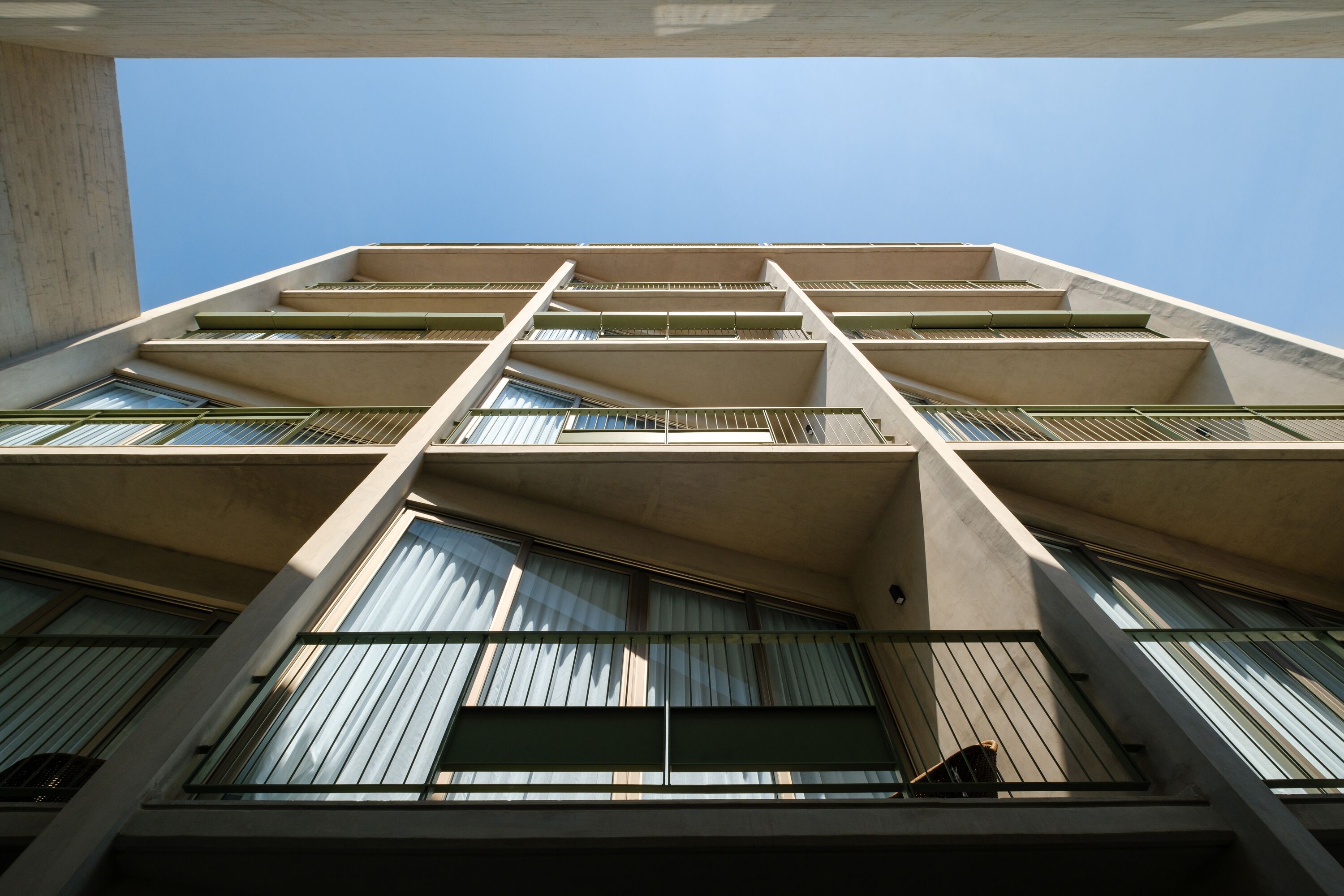 Un edificio alto con varios balcones y ventanas amplias.