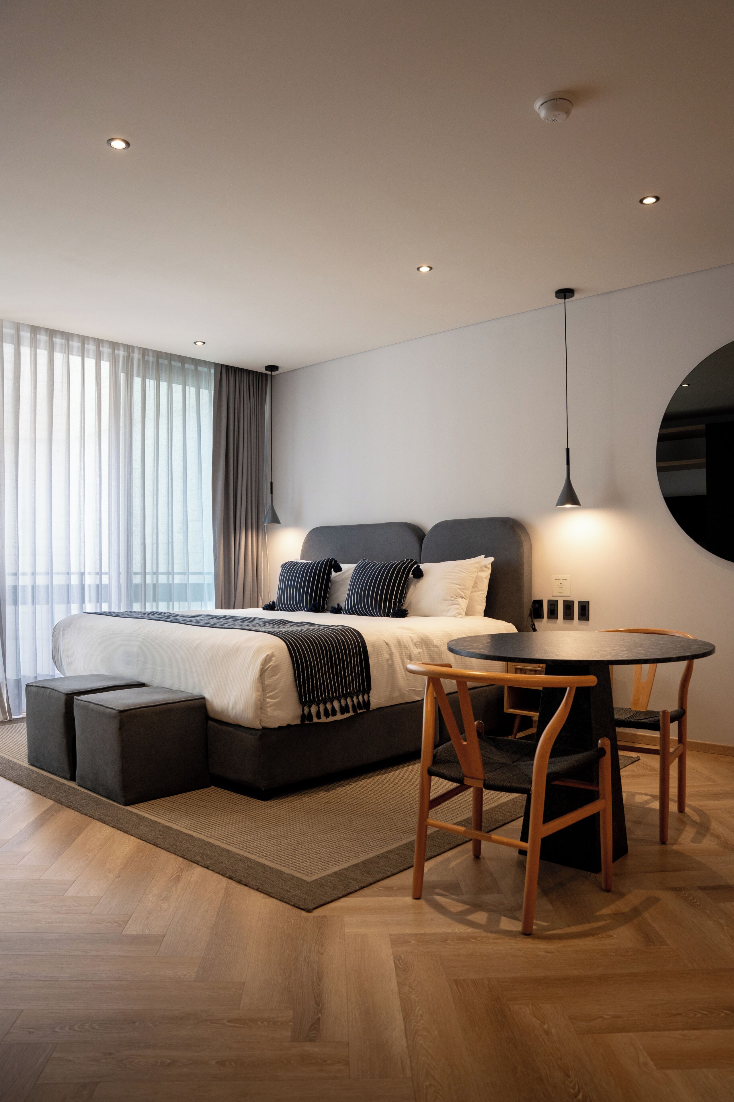 A modern bedroom with a bed, bedside table, and a round table with chairs.