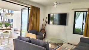 A modern living room with a flat-screen TV, two sofas, a glass coffee table, and a dining area with a white table and chairs. - Departamento Frente a la Playa, Salagua Manzanillo (Manzanillo)