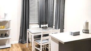 A compact kitchen with a dining area, a ceiling fan, and a window with blinds.