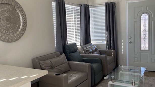 A modern living room with a sofa, a glass coffee table, and a door with a decorative window.