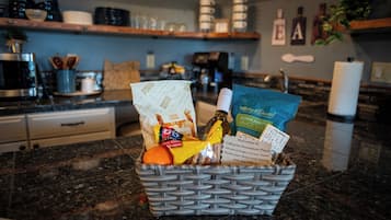 Un comptoir de cuisine avec un panier contenant des en-cas et une bouteille.