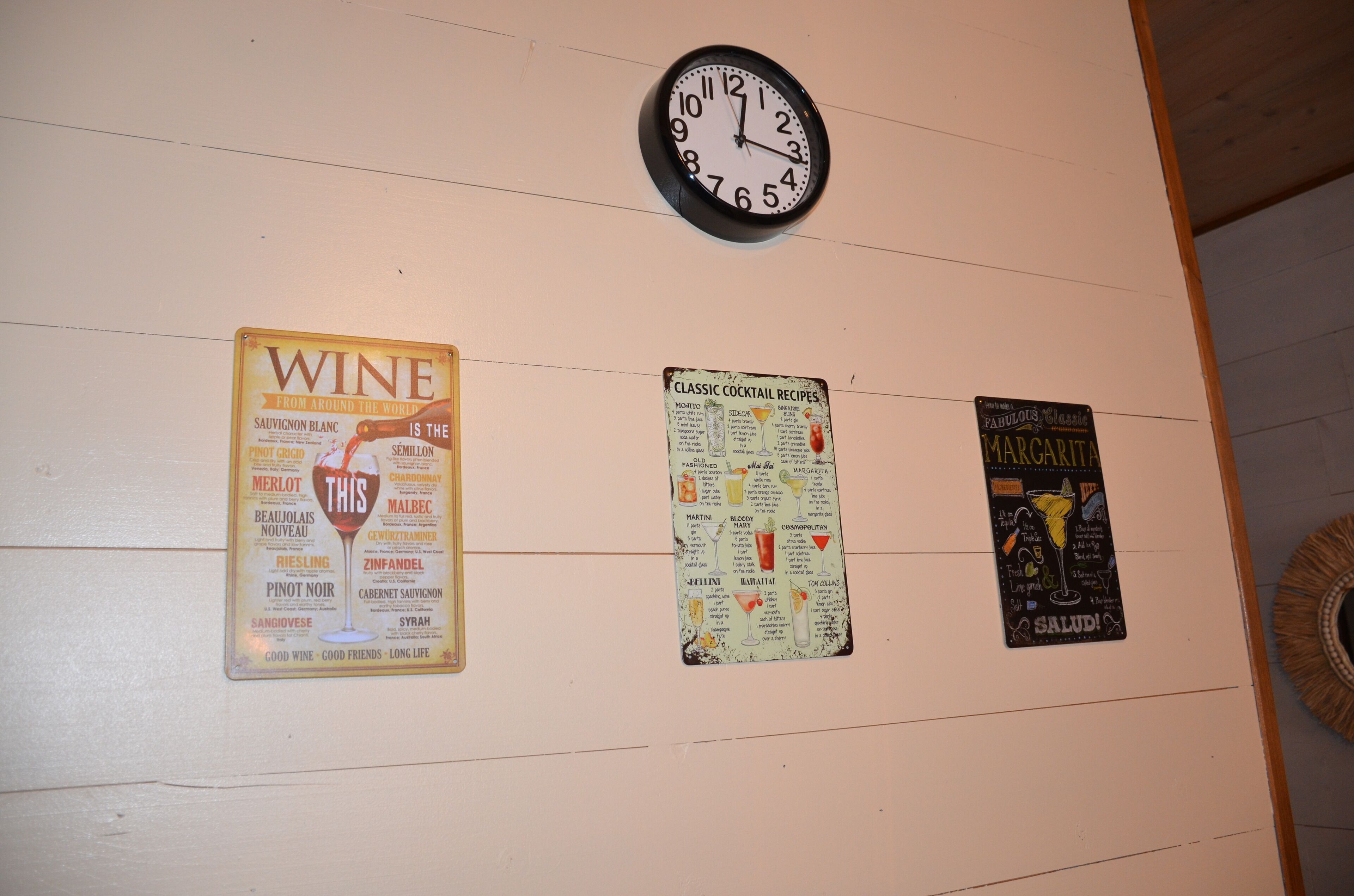 A wall with three posters: one about wine, one with classic cocktail recipes, and one for margarita.