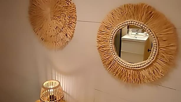 A wall with two decorative mirrors and a small console table with a lamp and a vase.