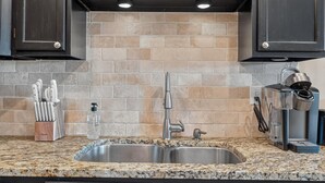 A kitchen with granite countertops, a double sink, and dark cabinetry. - Sandy's Beach Retreat (Miramar Beach)