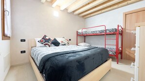 Ein Schlafzimmer mit Etagenbett, einem Bett mit gemusterten Kissen und einer Holzbalkendecke.