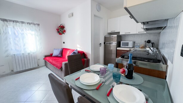 Een knus verblijf met een eethoek, kitchenette en een gezellige zithoek met een rode deken.