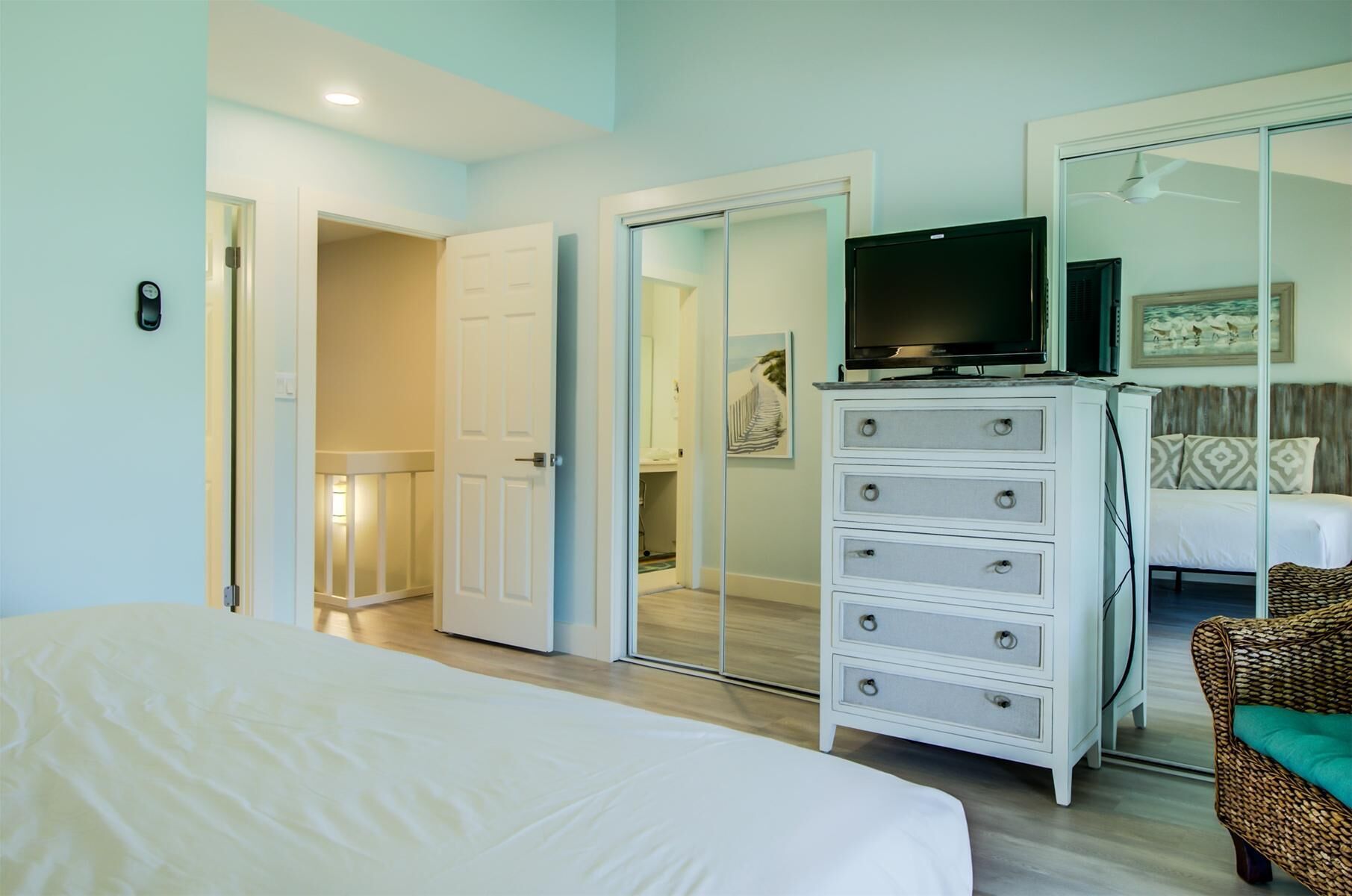 A bedroom with a bed, a dresser, a television, and a mirror.