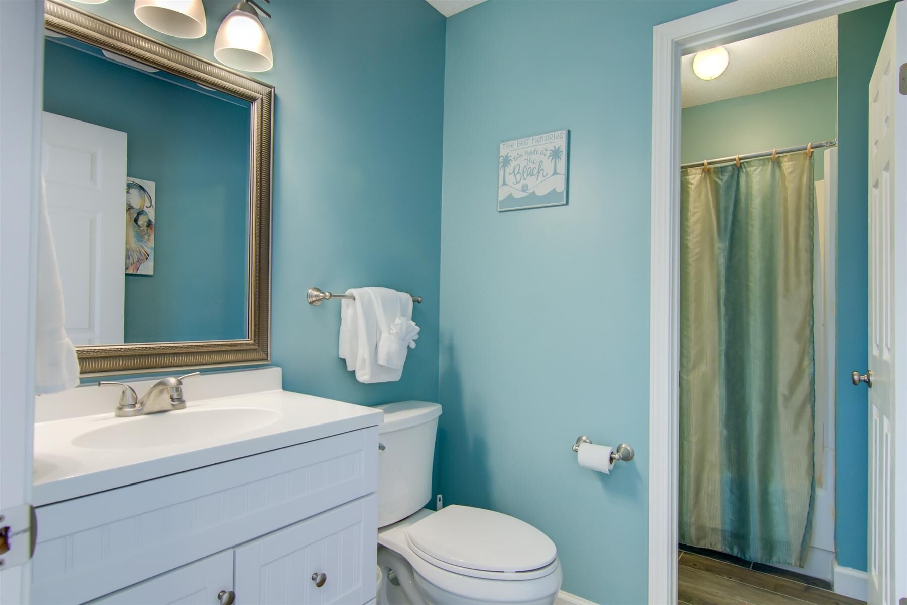 Un baño con lavamanos blanco, inodoro y cortina de ducha.