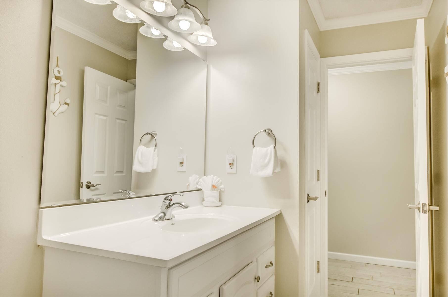Une salle de bain avec un meuble-lavabo blanc, un grand miroir et un luminaire au plafond.