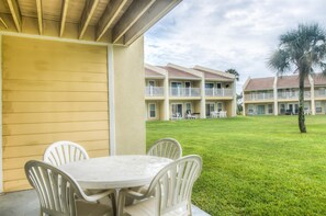 A hotel with a covered outdoor seating area, multiple balconies, and a well-maintained lawn. - 7 D, One Bedroom Condo (Destin)