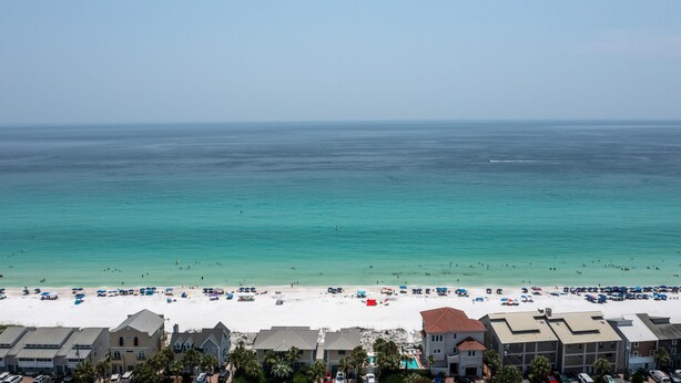 A beach with clear turquoise water, white sand, and a row of beach houses in the foreground. - 7 D, One Bedroom Condo (Destin)
