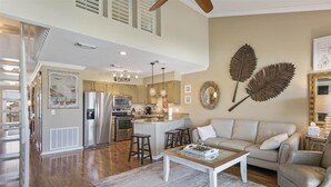 A spacious living area with a wooden floor, a beige sofa, a coffee table, and a kitchen with modern appliances. - 8 G Two Bedroom Condo (Miramar Beach)