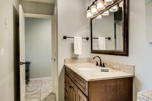 A bathroom with a granite countertop, a dark wood vanity, a large mirror with lights, and a towel rack. - 9 H Two Bedroom Condo (Miramar Beach)