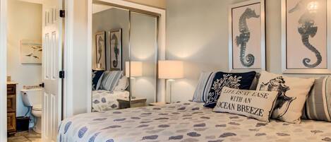 A bedroom with a bed, a nightstand, a mirror, and artwork on the walls.