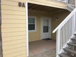 A yellow building with a white door and a staircase leading to a second floor. - 9 A, One Bedroom Condo (Miramar Beach)