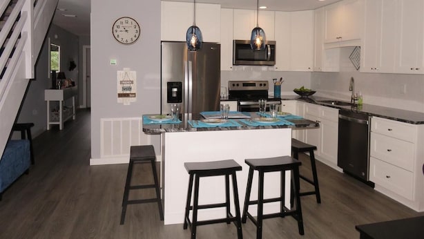 A modern kitchen with white cabinets, stainless steel appliances, and a central island with stools. - 10e, Our Happy Place (Miramar Beach)