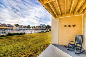 A hotel with a covered porch, a concrete walkway, and a view of other hotel buildings in the background. - Settle on the Sand (Miramar Beach)