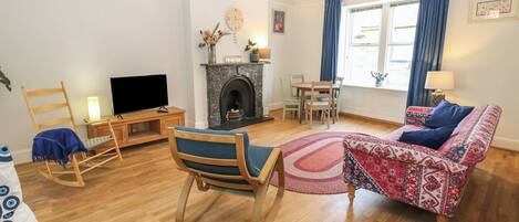 Uma sala de estar com lareira, televisão, sofá e mesa de jantar.