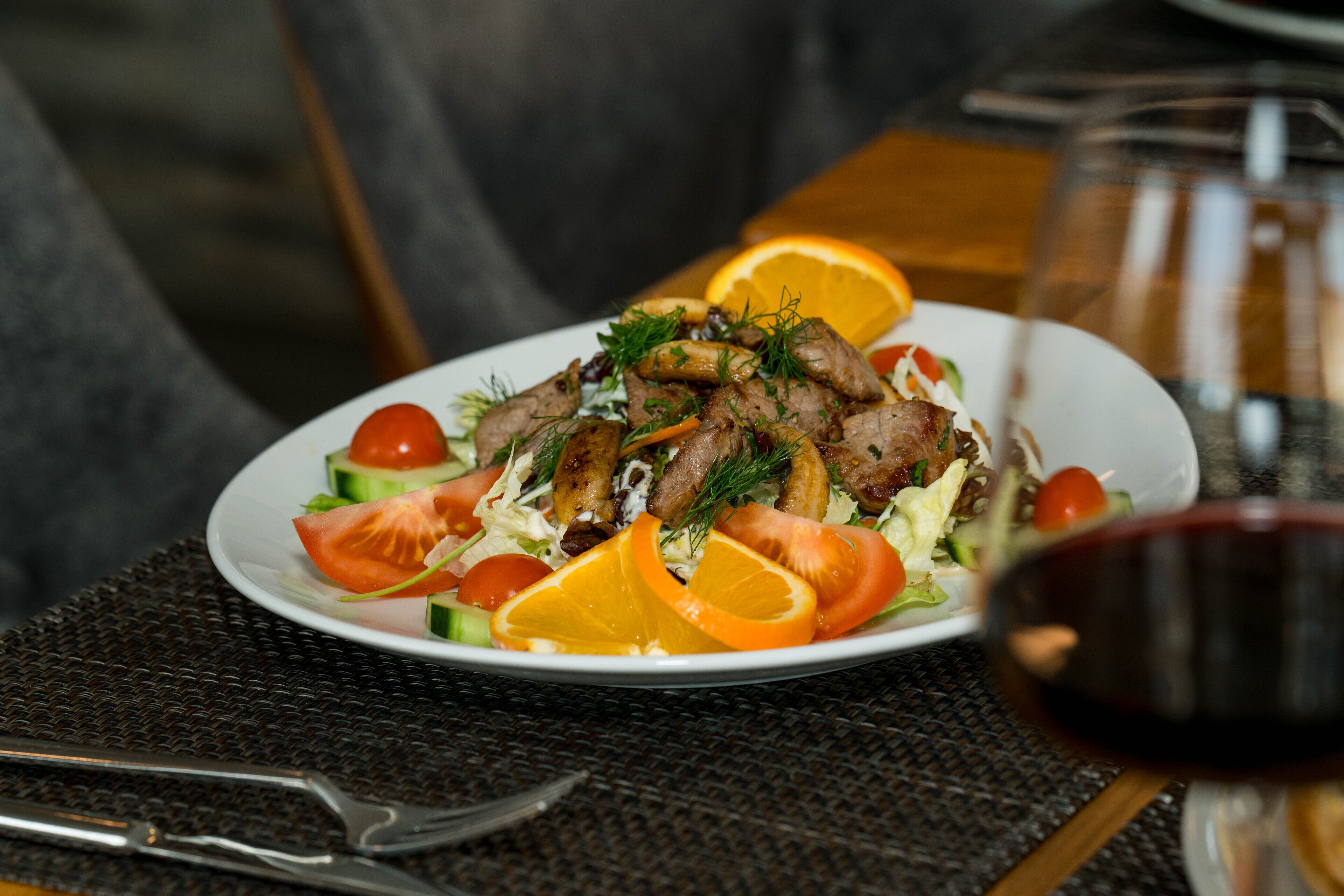 A plate of food with a glass of red wine and a bottle in the background.